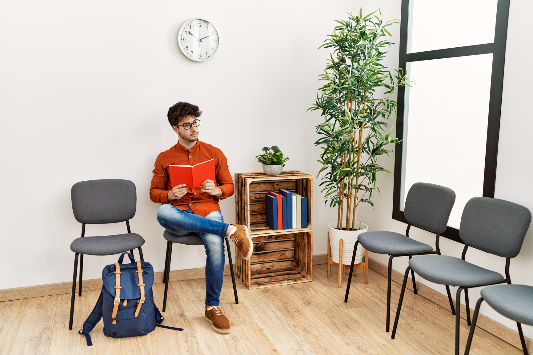 Young hispanic man reading book at waiting room